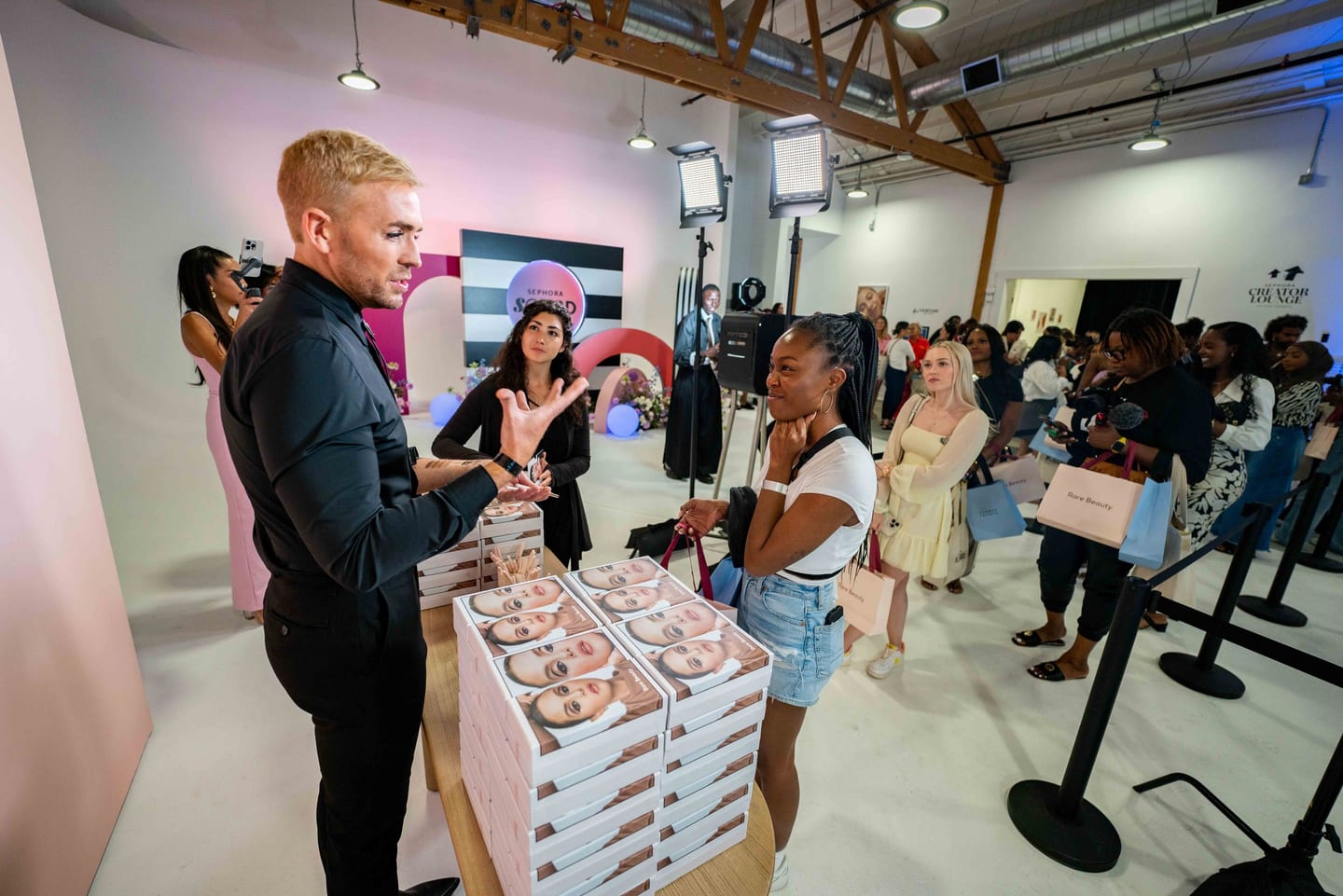 Makeup artist speaking with creators at the Sephora Squad Creator Lounge with Rare Beauty gift bags