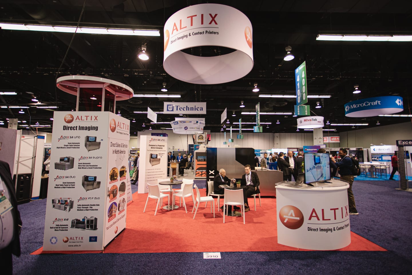 The Altix direct imaging booth with a round hanging sign on the IPC APEX EXPO exhibit floor, other exhibitor booths behind it
