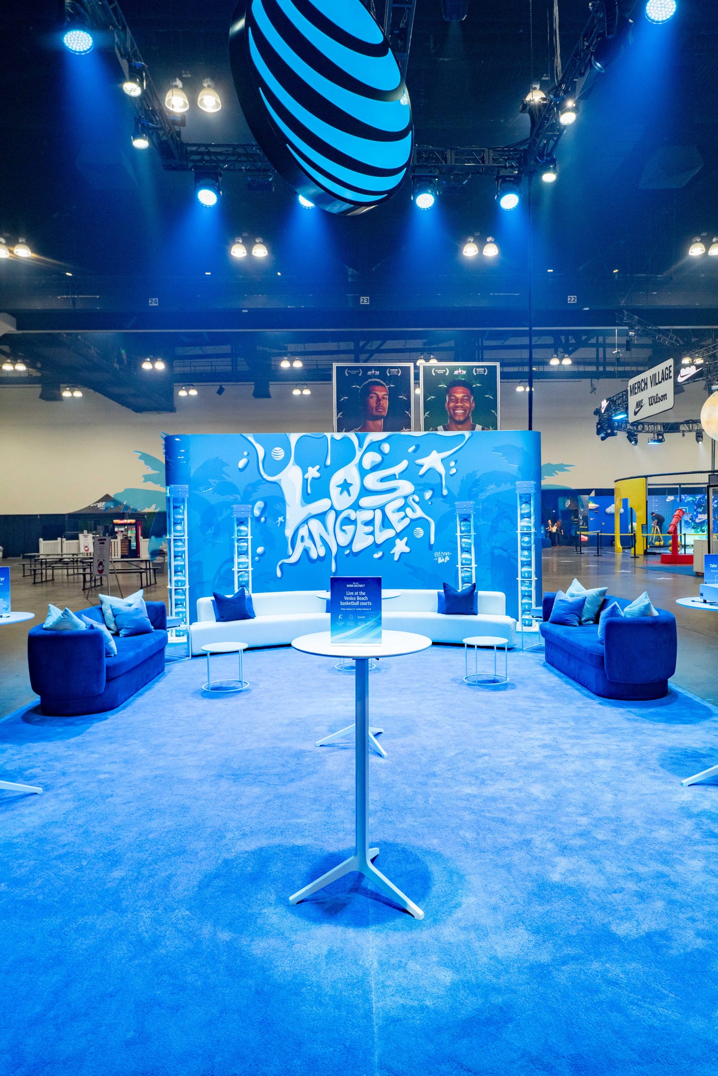 A blue AT&T-branded lounge with a Los Angeles graffiti mural under a giant AT&T globe at the AT&T Dunk District activation for NBA All-Star in Los Angeles