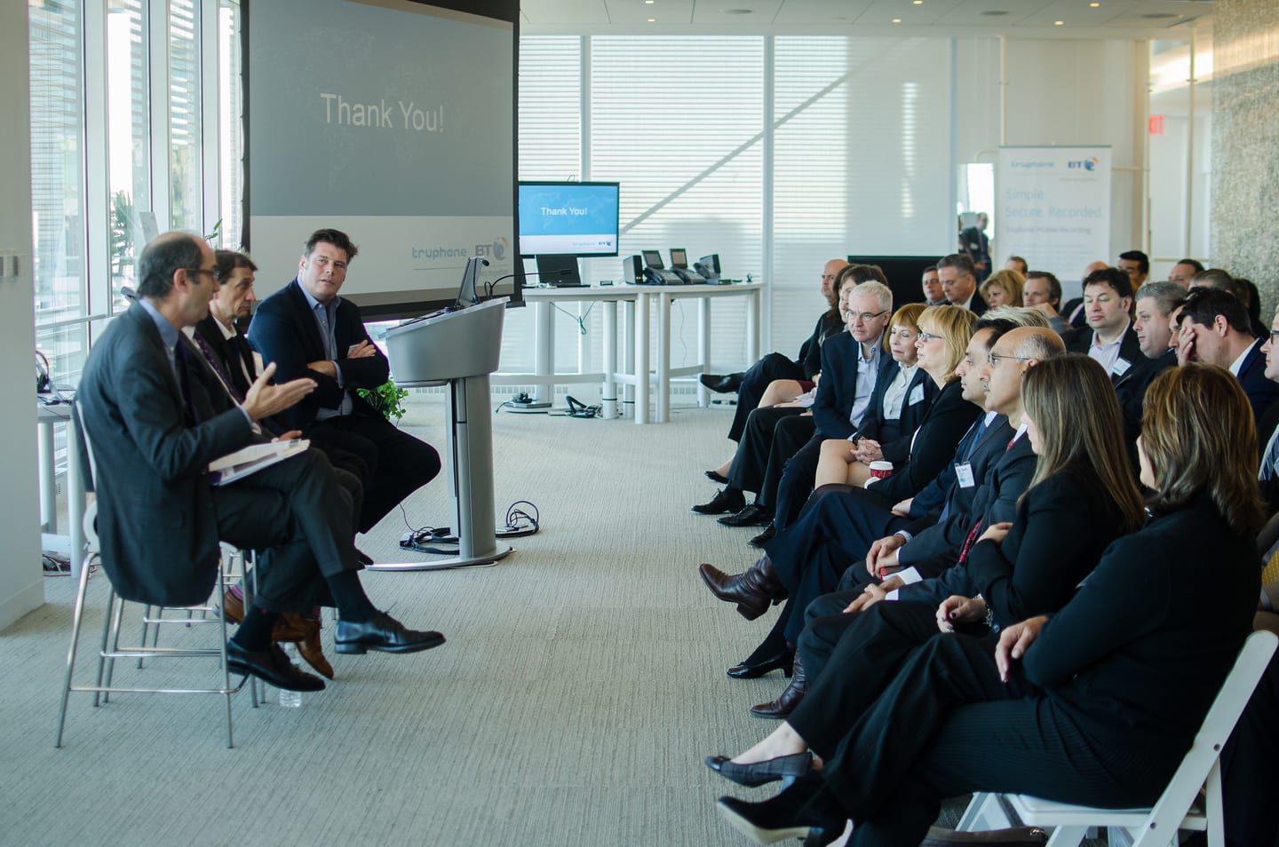 Four panelists seated beside a window with a “Thank you” slide on screen and an audience in the foreground, New York