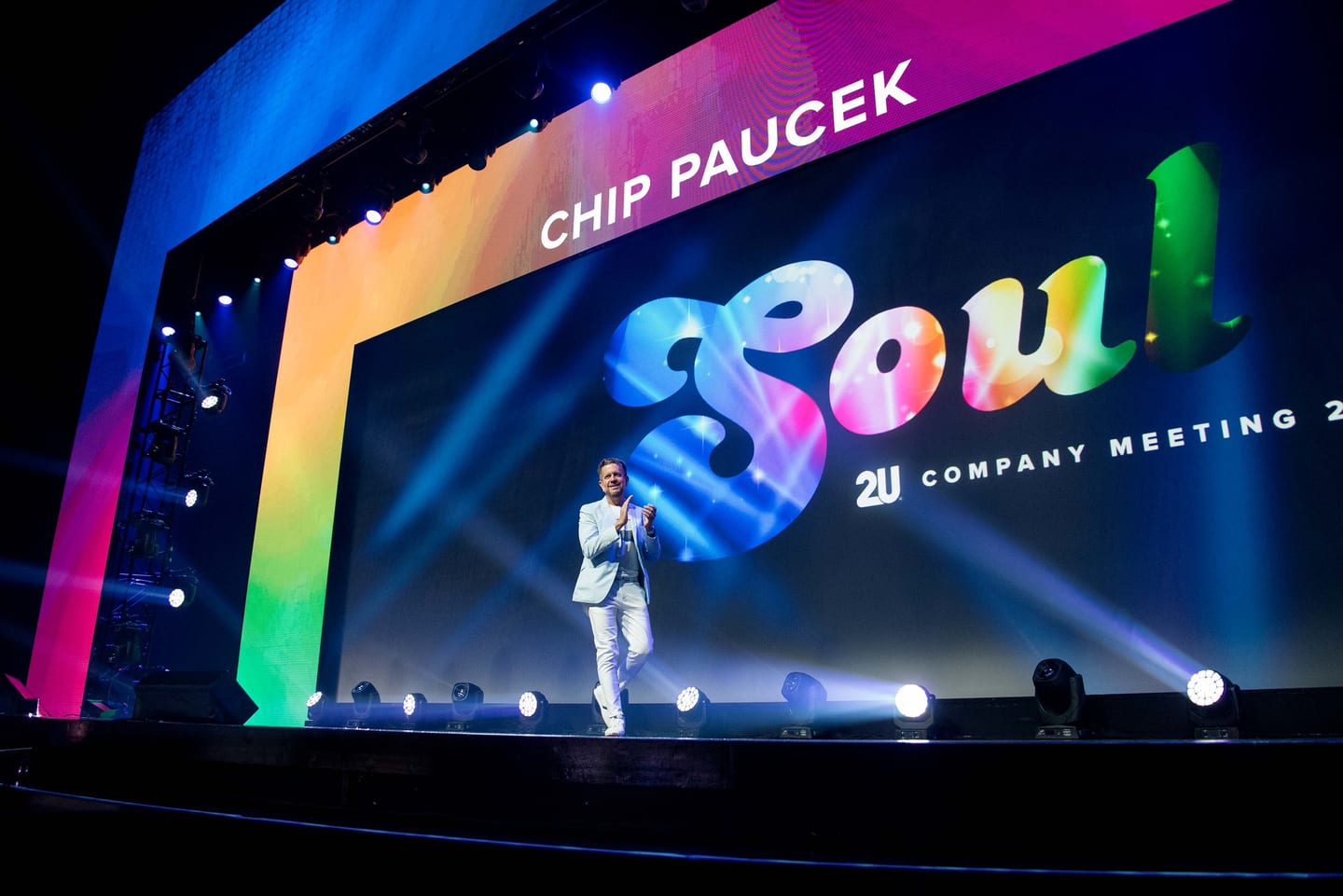 2U co-founder Chip Paucek on a large rainbow-lit stage at the 2U SOUL company-meeting keynote