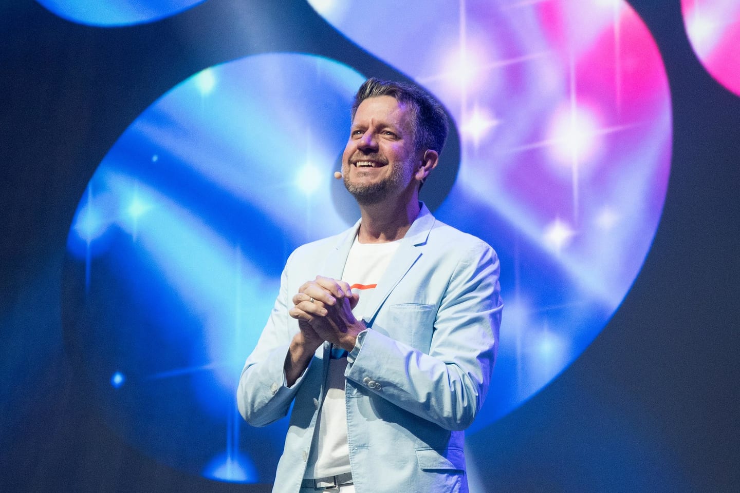 2U co-founder Chip Paucek in a light-blue blazer on stage against the SOUL company-meeting backdrop