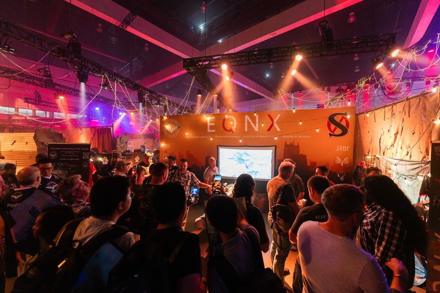Fans gathered under stage lighting at the EQNX Star Citizen LAN party on the community floor at CitizenCon, held at the Los Angeles Convention Center