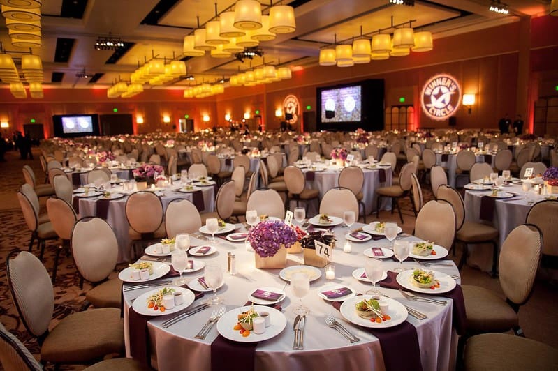 A hotel ballroom set with round tables for a corporate general session
