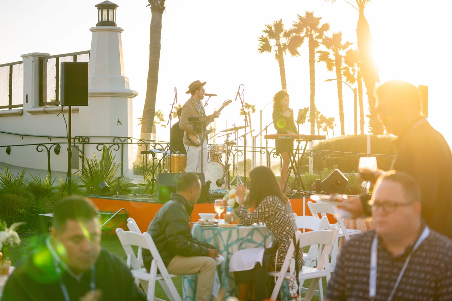 A live band performing on an outdoor stage at a corporate dinner by the water