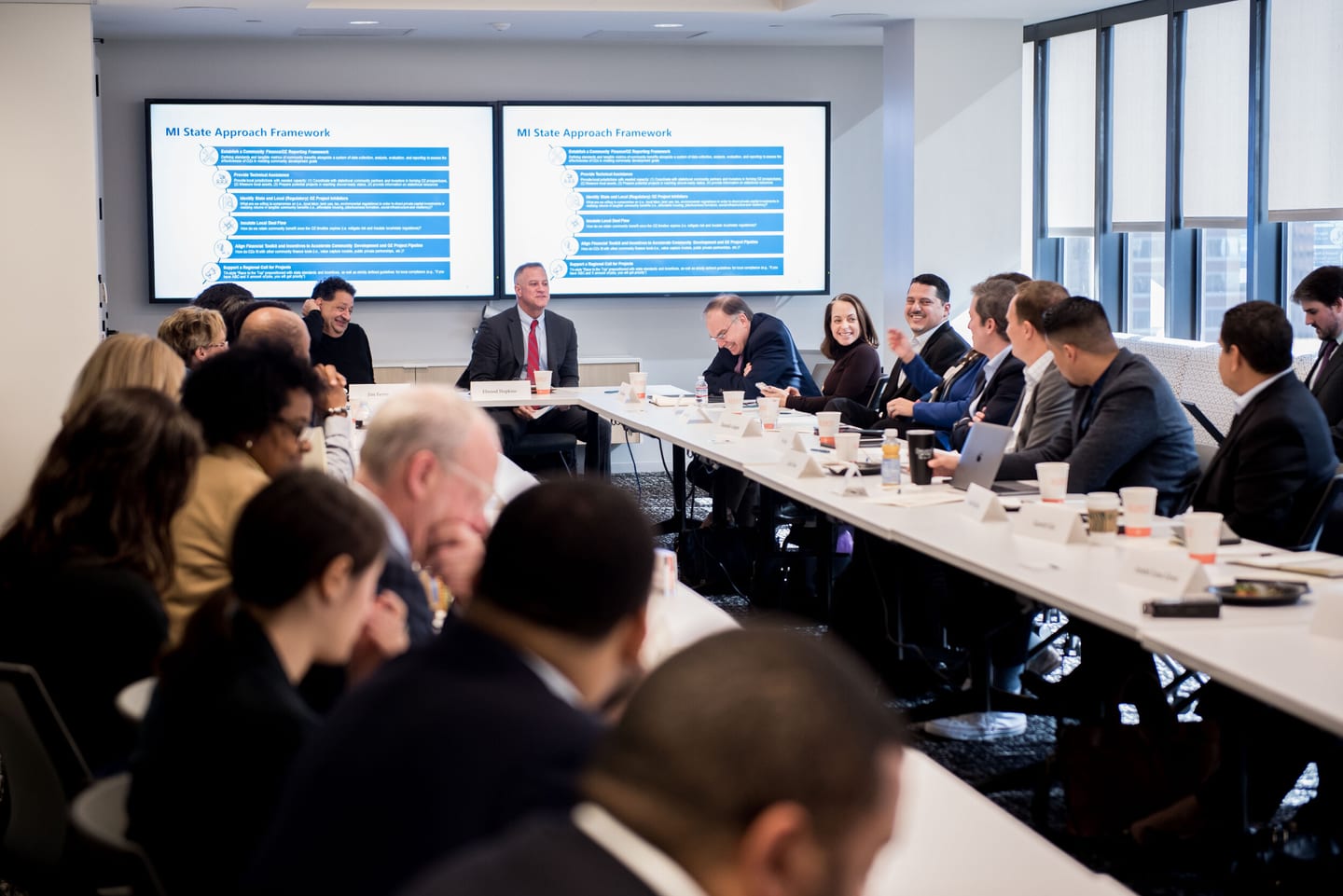 Executives around a boardroom table before presentation screens at a downtown Los Angeles meeting