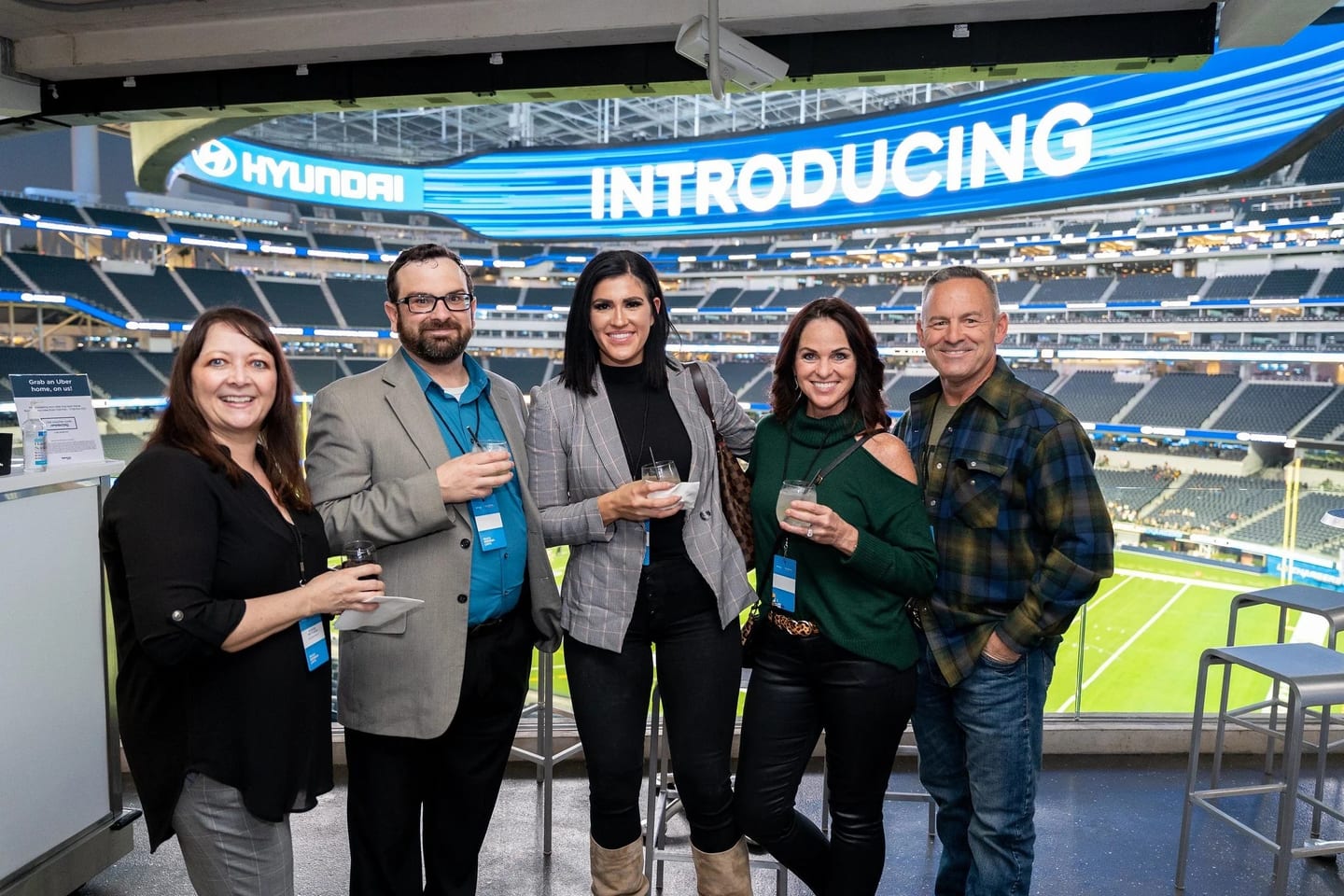 A corporate group with drinks in a SoFi Stadium suite overlooking the field at a Hyundai event