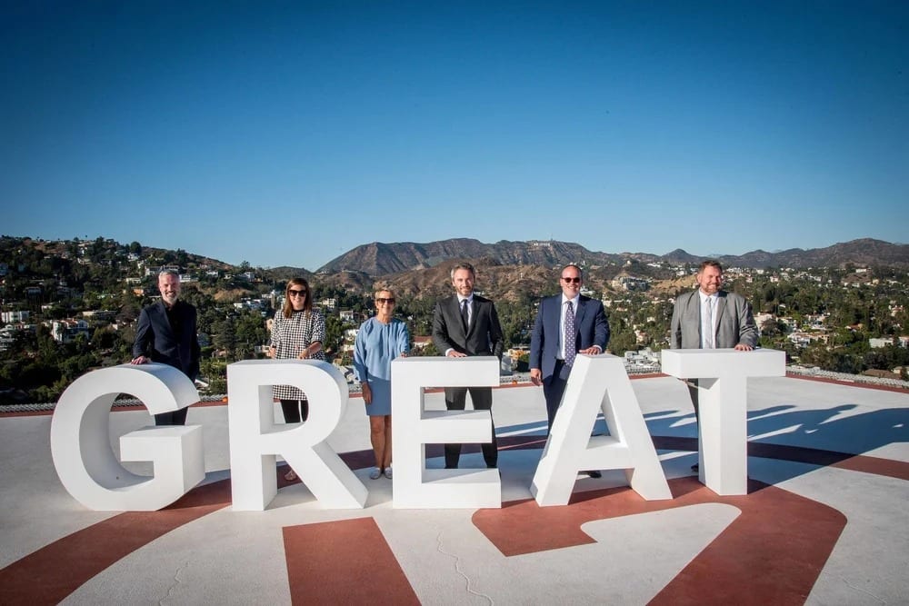 Corporate team posing behind giant GREAT letters on a rooftop with the Hollywood Hills behind them