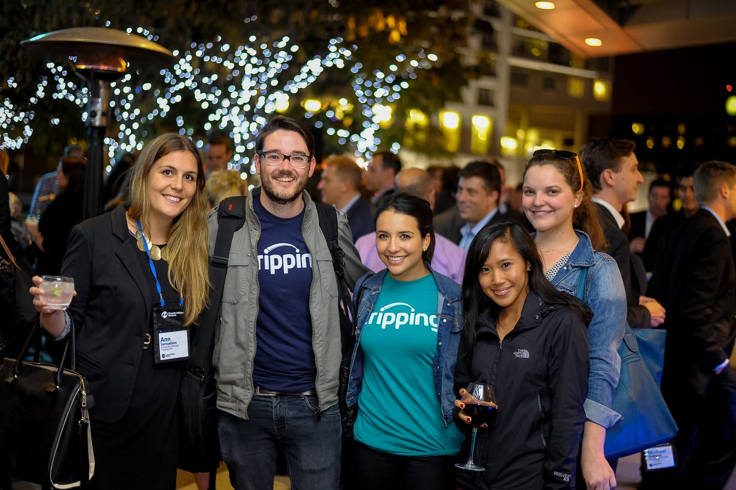 Five guests with drinks under string lights at an Expedia Affiliate Network networking reception in Downtown Los Angeles