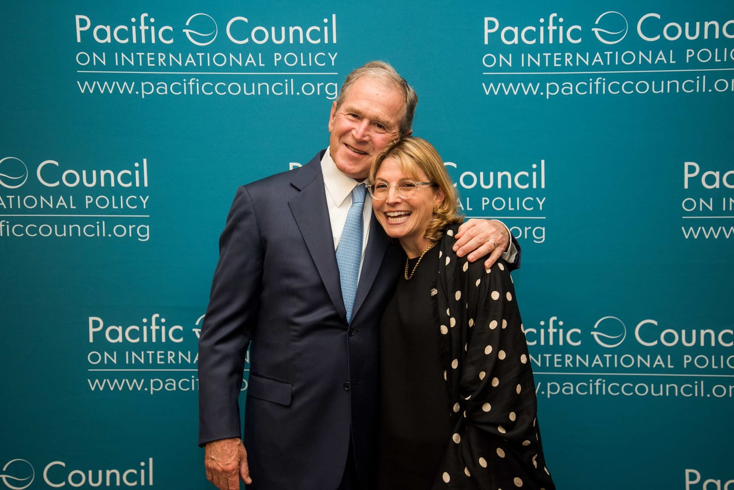 Former U.S. President George W. Bush posing with a guest at the Pacific Council on International Policy step-and-repeat in downtown Los Angeles