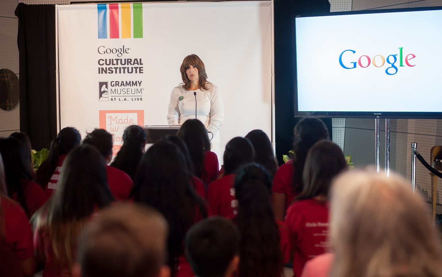 A speaker at a Google Cultural Institute podium in front of a seated audience at the Grammy Museum