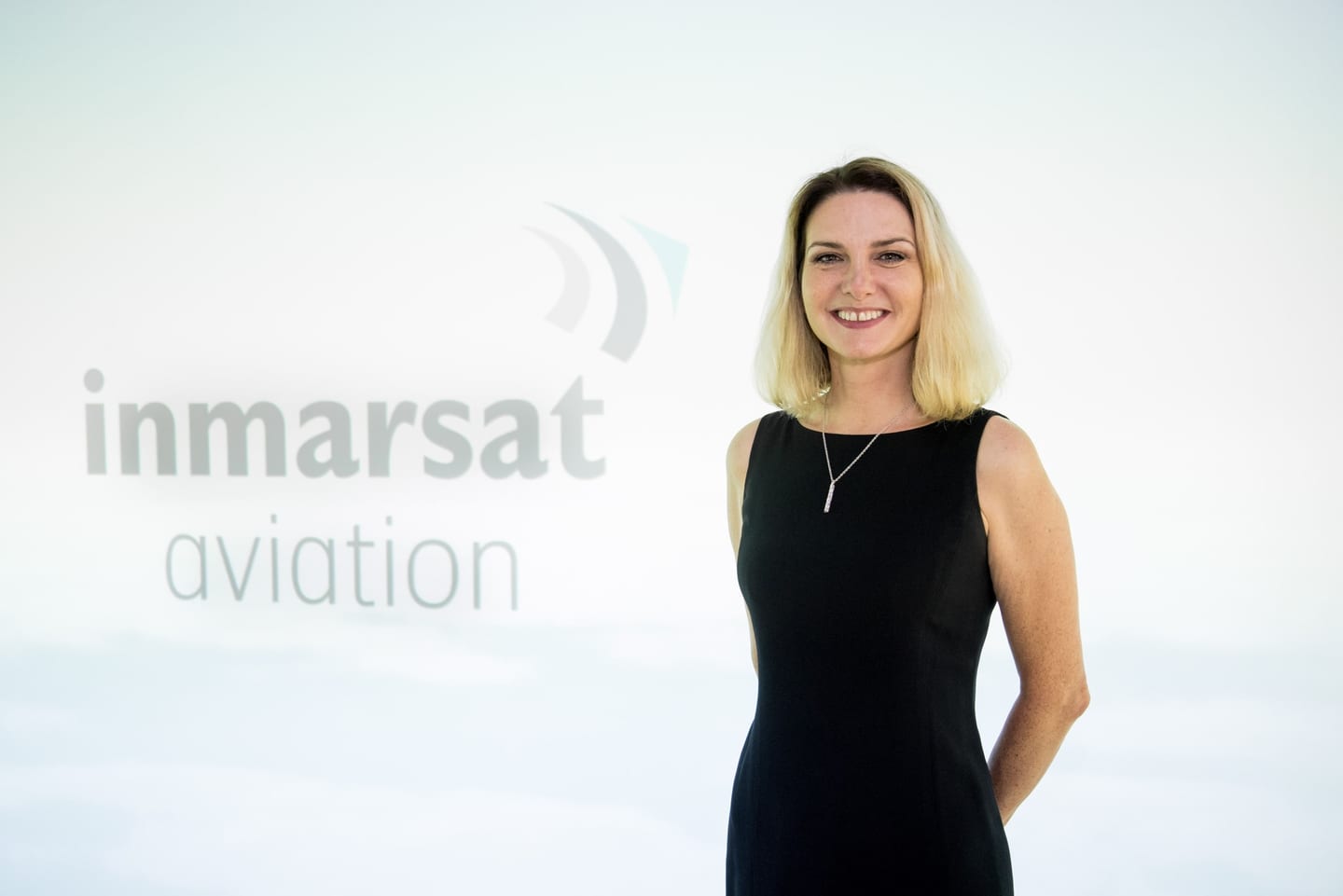 A woman in front of an Inmarsat Aviation backdrop at a corporate event