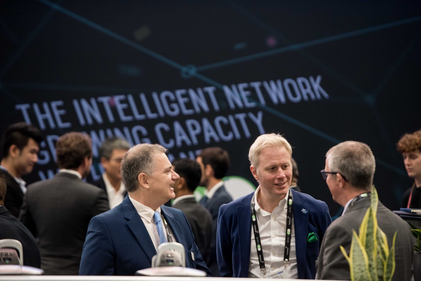 Attendees at the Inmarsat Aviation booth beneath The Intelligent Network on Board signage on the APEX EXPO trade-show floor