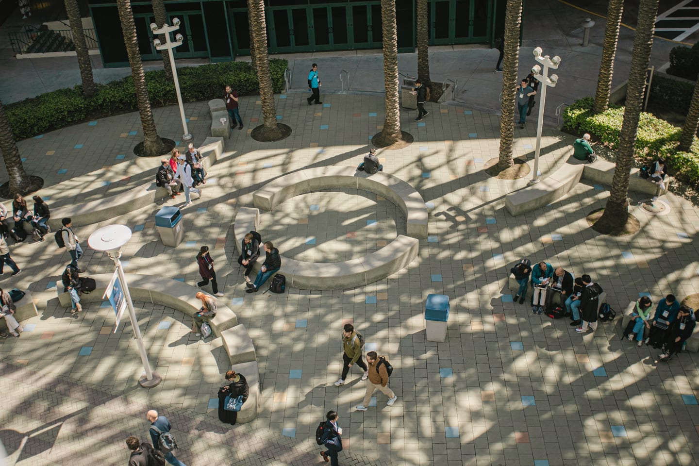 Attendees crossing the palm-lined outdoor concourse at IPC APEX EXPO at the Anaheim Convention Center