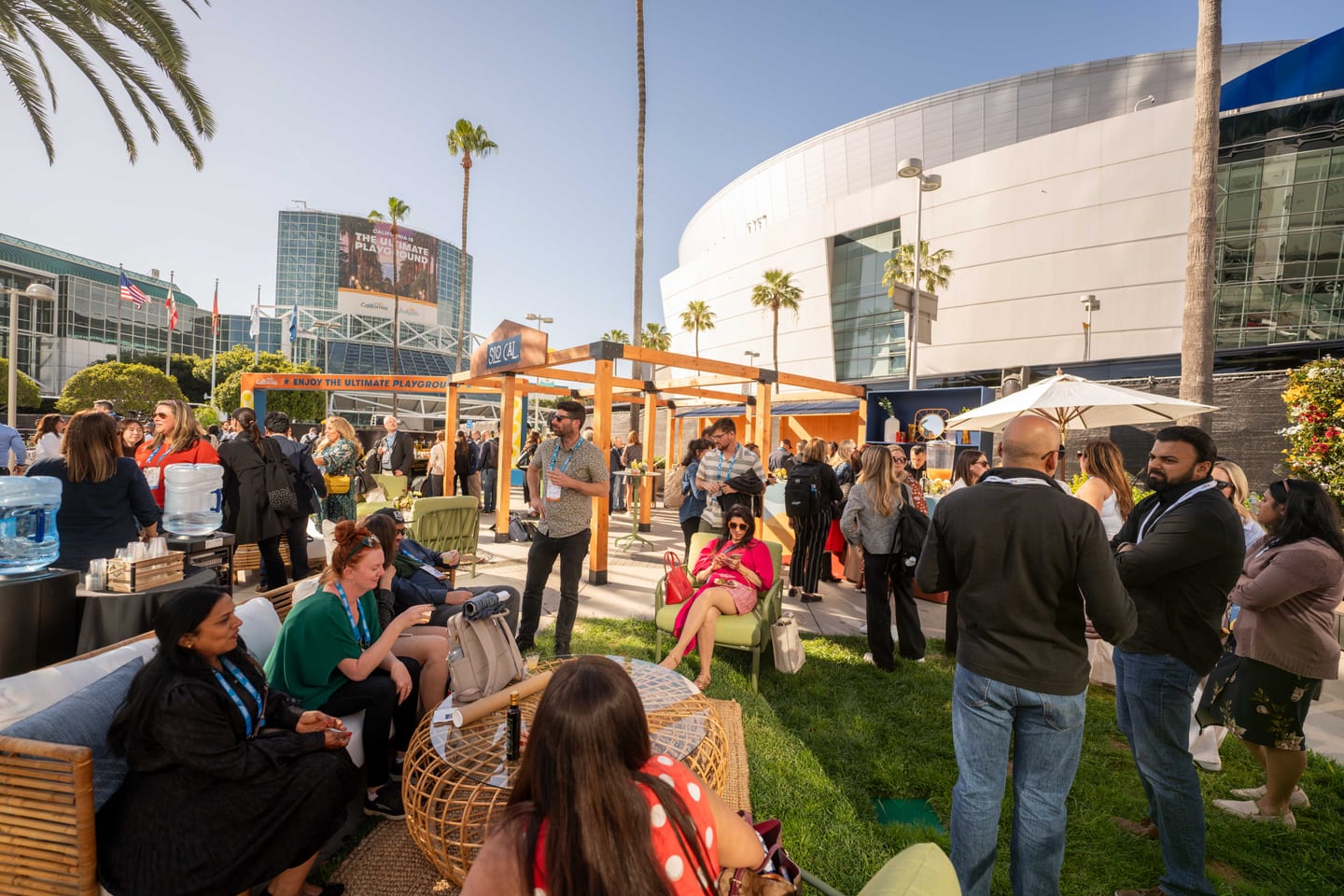 A wide exterior view of the Los Angeles Convention Center with Visit California branding and an outdoor IPW event area