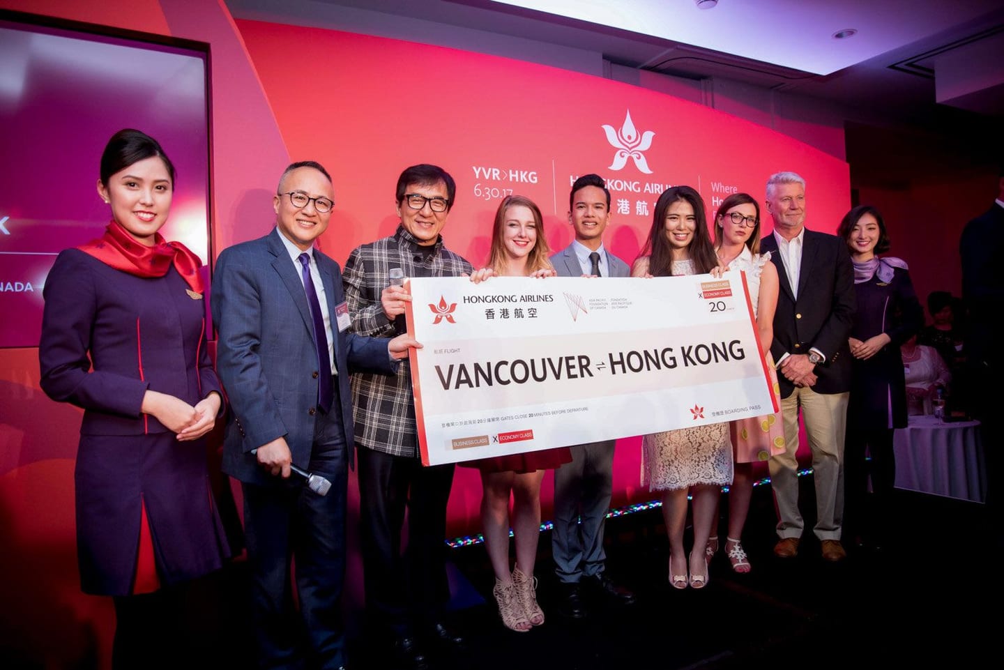 Jackie Chan at a Hong Kong Airlines route launch event, holding a Vancouver–Hong Kong sign