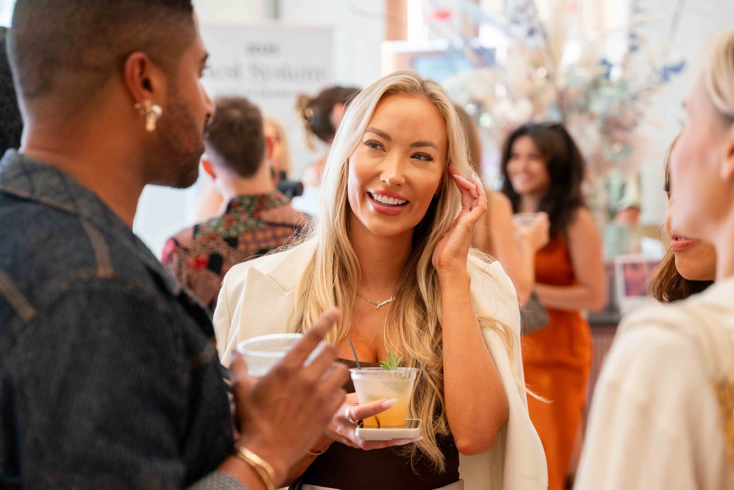 A guest smiling in conversation with a drink at the Marini SkinSolutions skincare pop-up