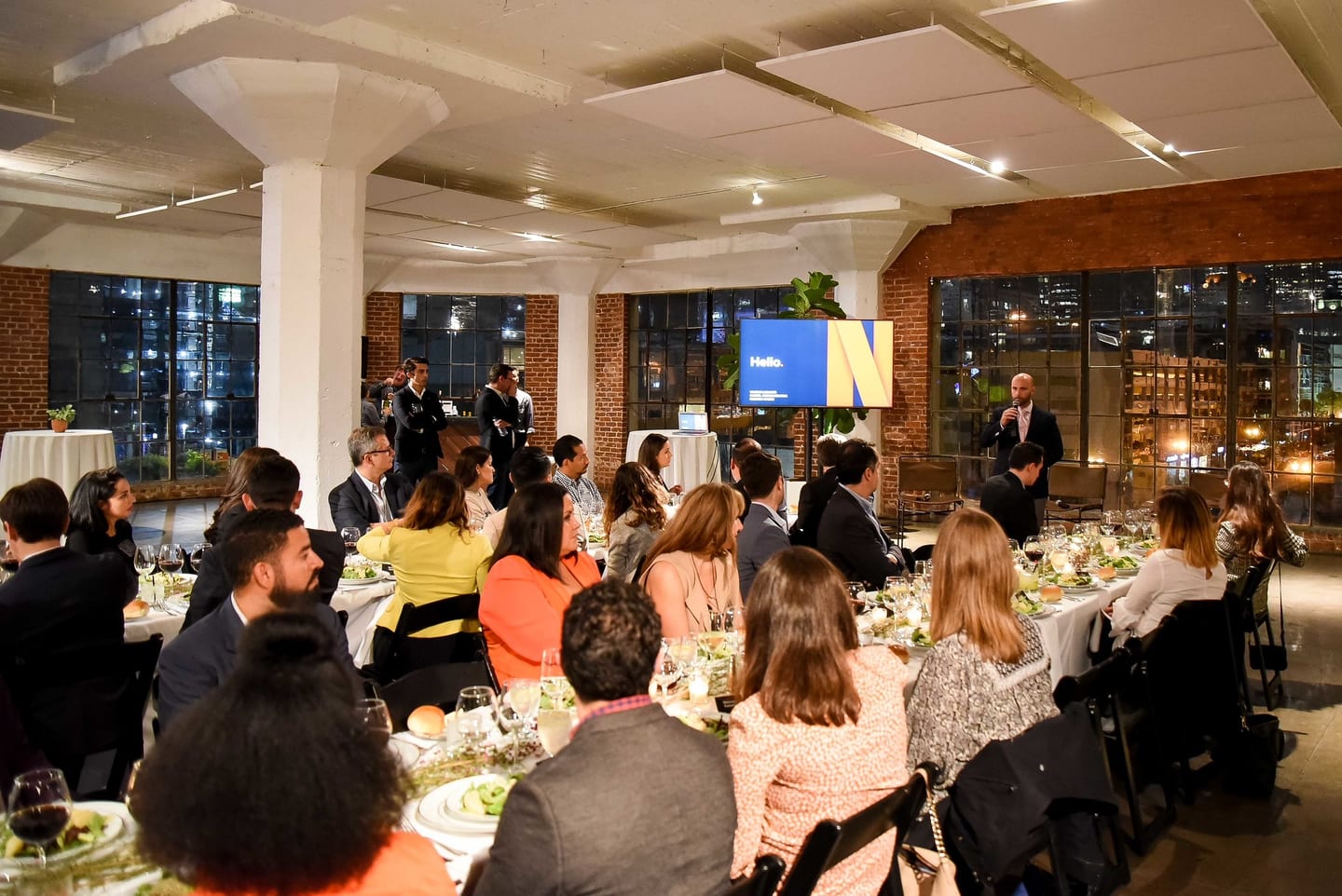 Seated guests at a Netflix dinner reception with the Netflix logo on screen in a warm brick venue in Hollywood
