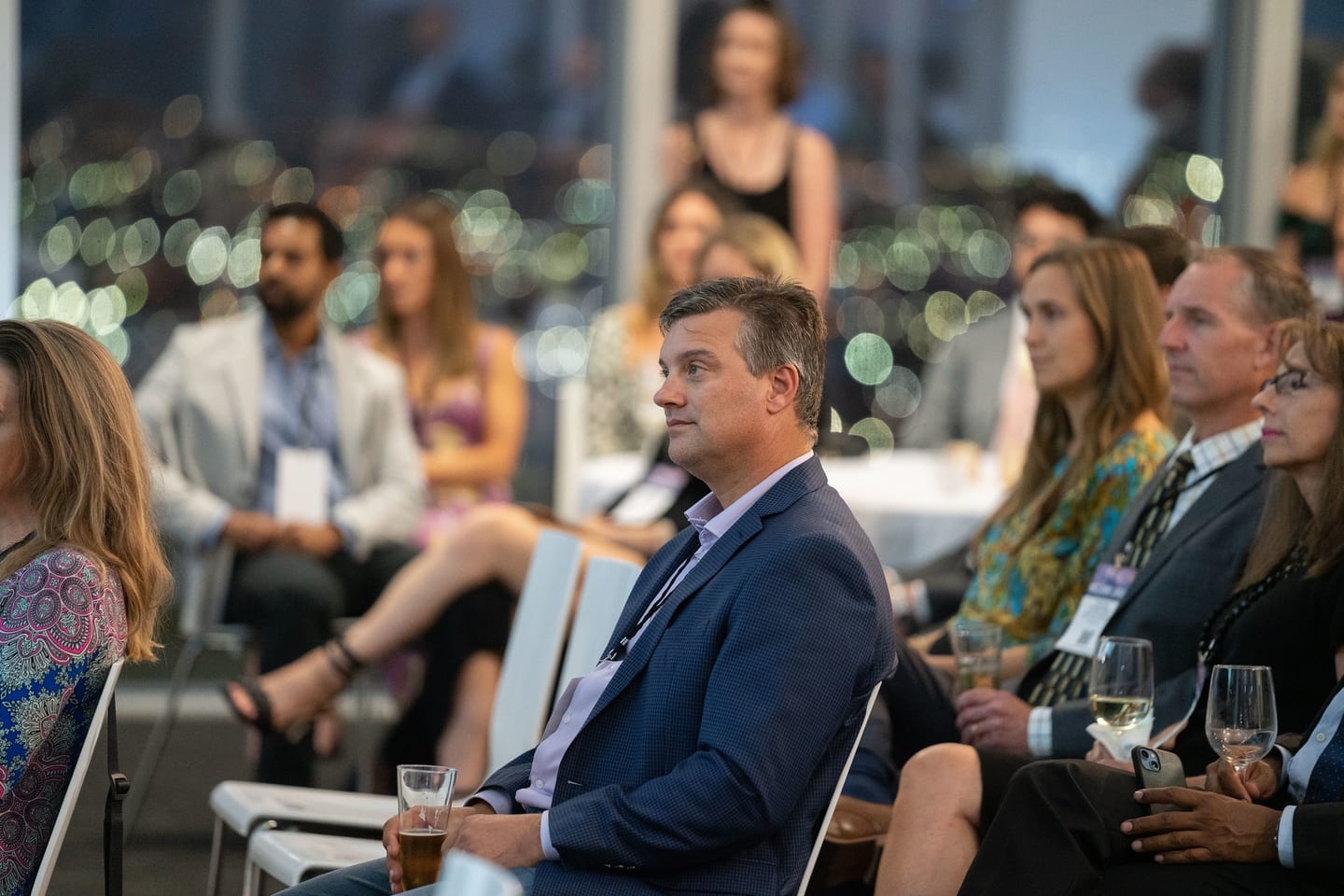 An audience seated by floor-to-ceiling windows at dusk during a NetZero summit talk on a Downtown LA rooftop