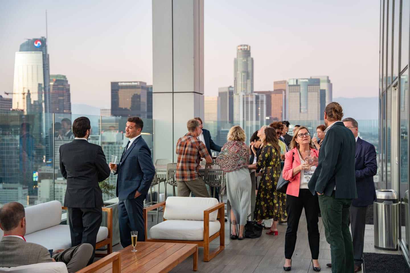 Guests mingling at a rooftop reception overlooking the Downtown Los Angeles skyline at golden hour