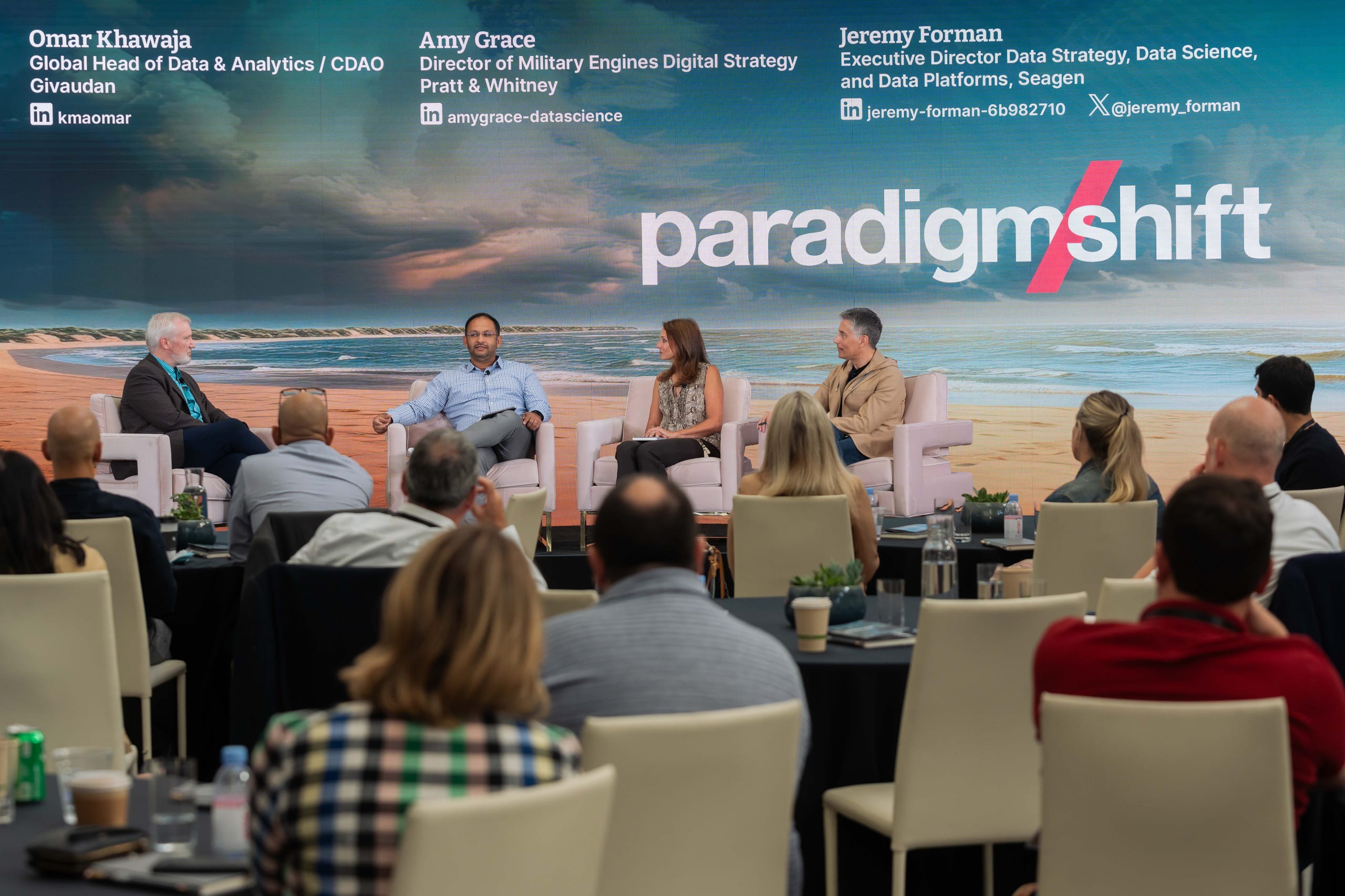Four executives seated on stage for a data-strategy panel before a seated audience at the Paradigm Shift conference