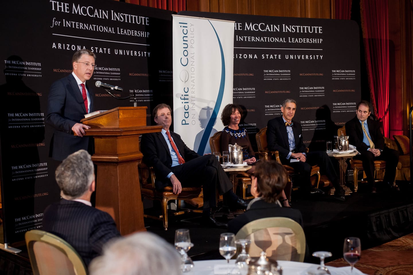 Speaker at a podium beside a seated panel at a Pacific Council policy summit