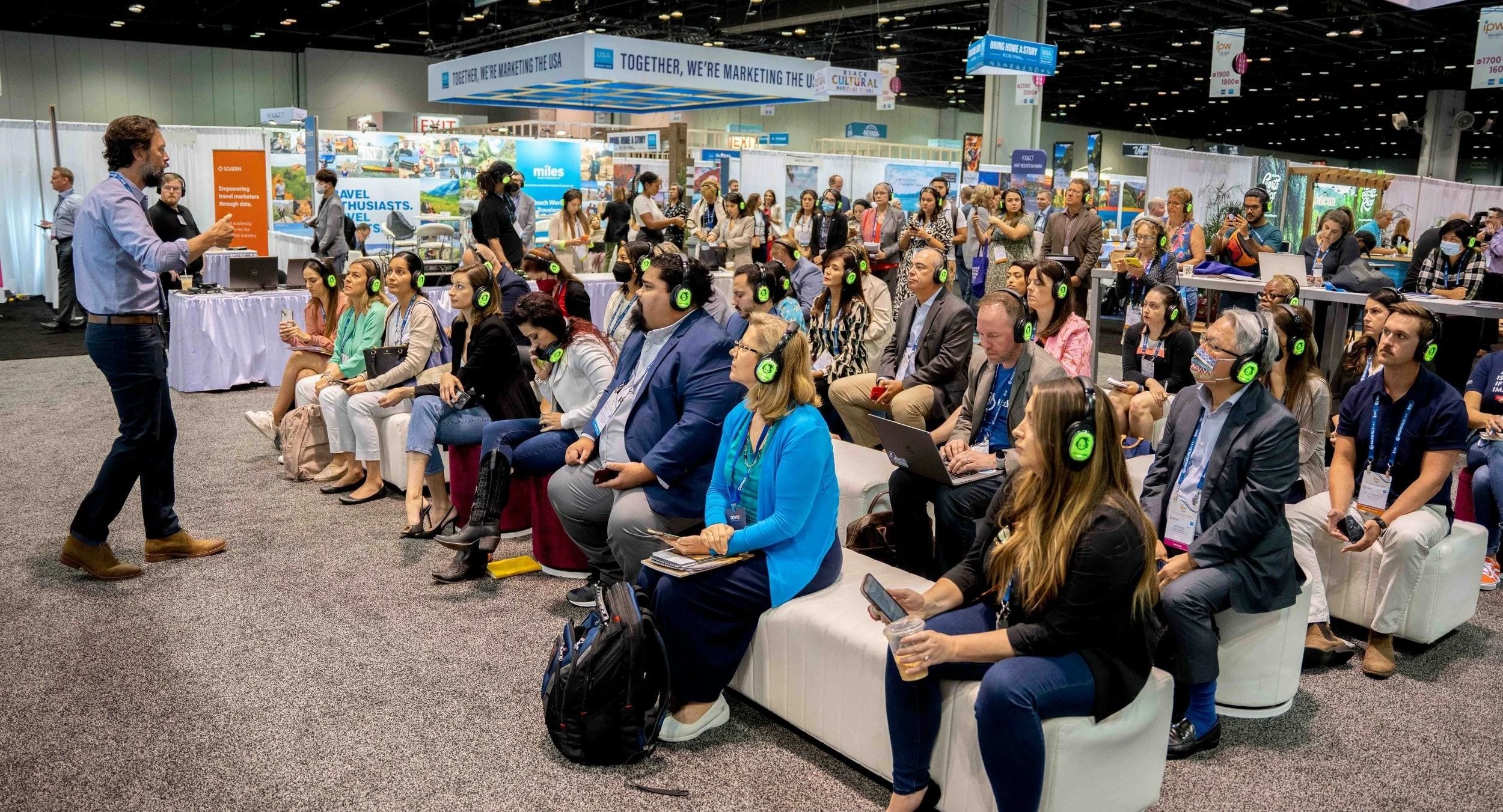 Large seated audience wearing wireless headphones at a corporate general session