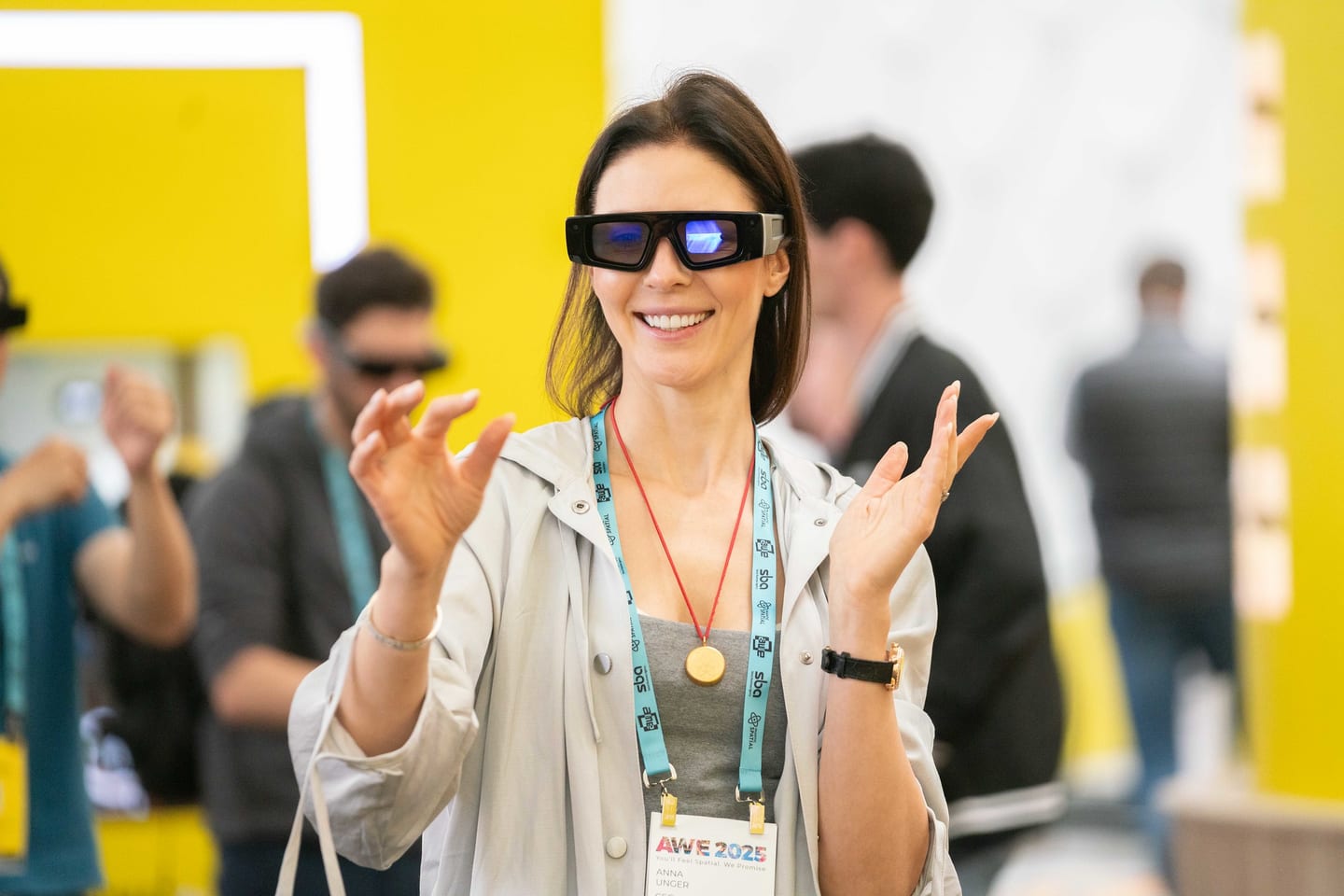 A smiling attendee gesturing while wearing Snap AR Spectacles at Augmented World Expo