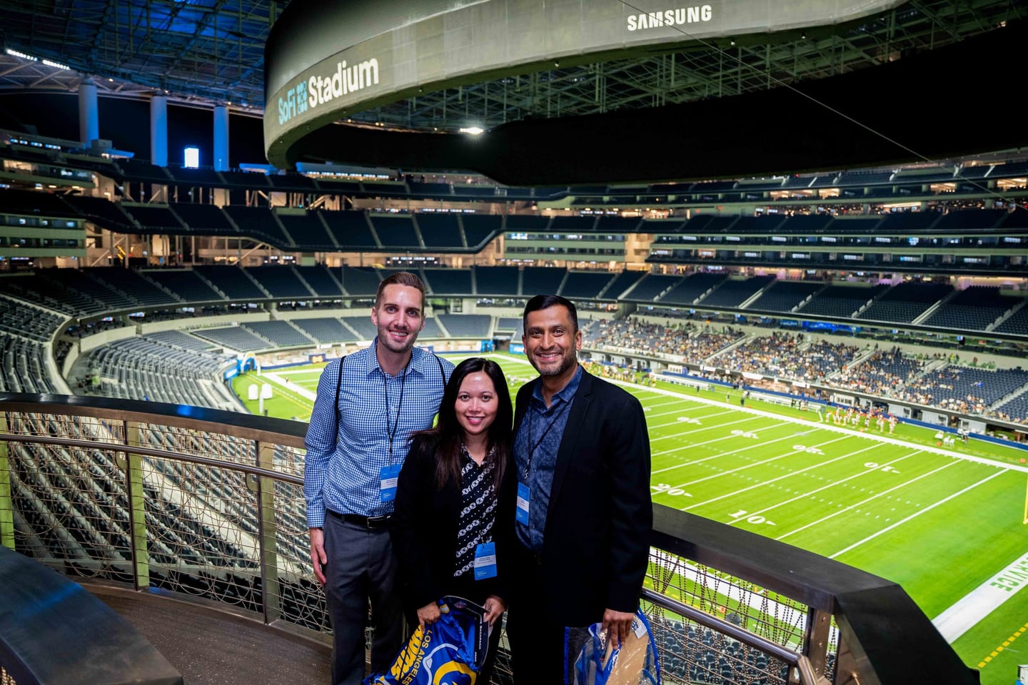 Corporate guests with badges in a suite overlooking the field at SoFi Stadium