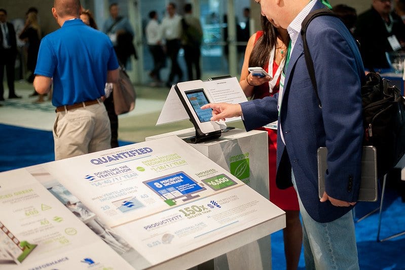 Exhibitor demonstrating a product on a tablet at a trade show sponsor booth