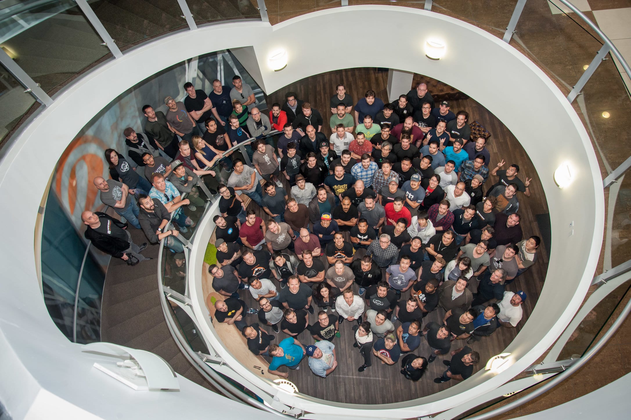 Overhead group photo of a large company all-hands meeting in a spiral atrium