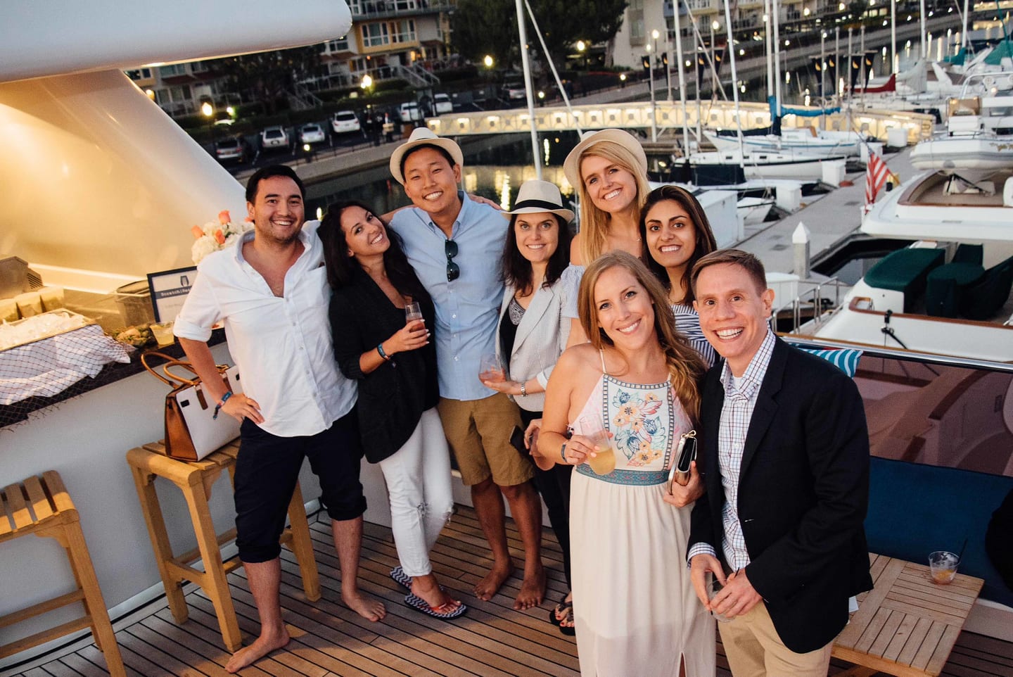 Five guests posing together on a yacht deck with the marina behind them